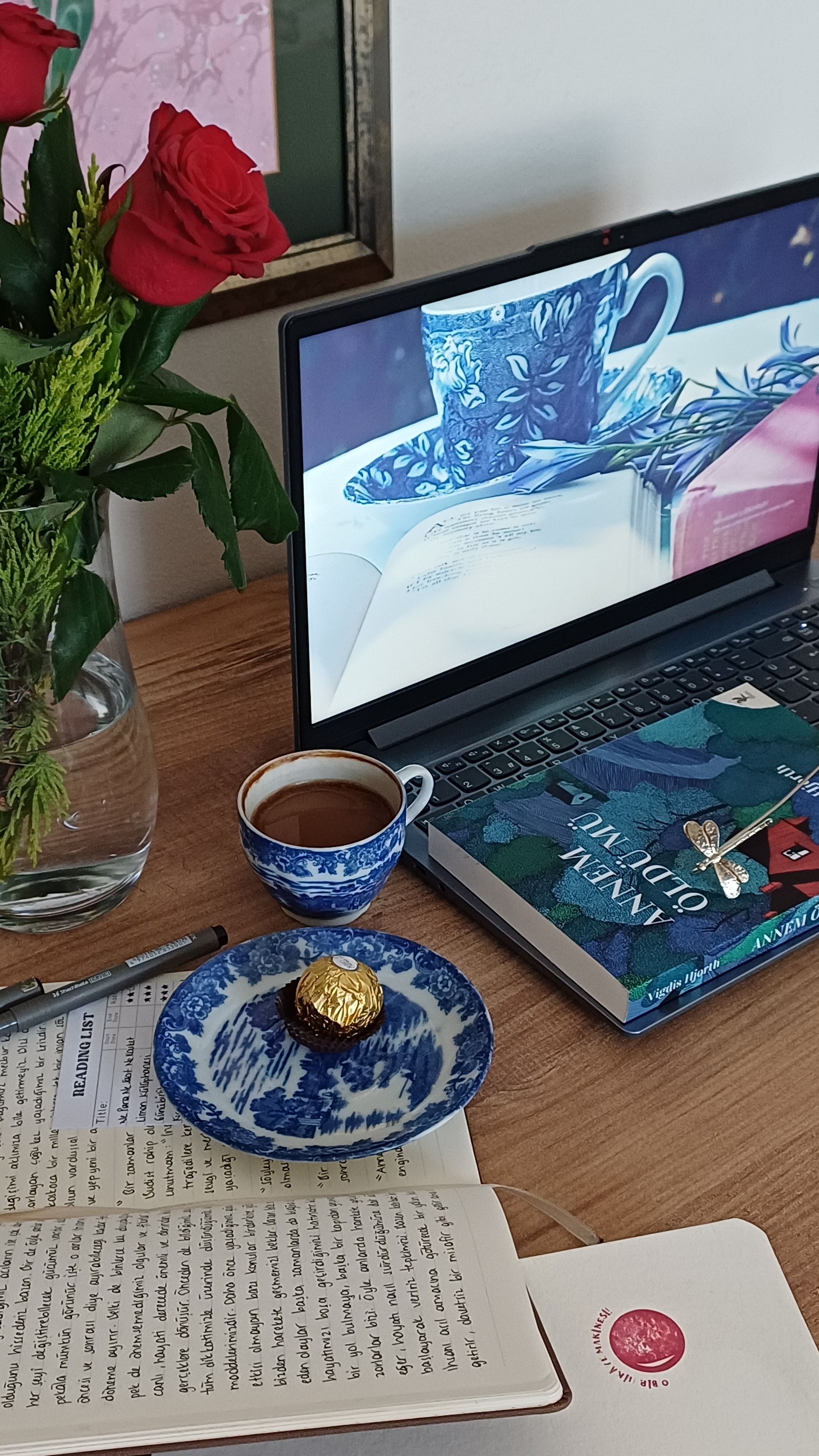 Warm home office scene featuring a laptop, coffee, and book with red roses.