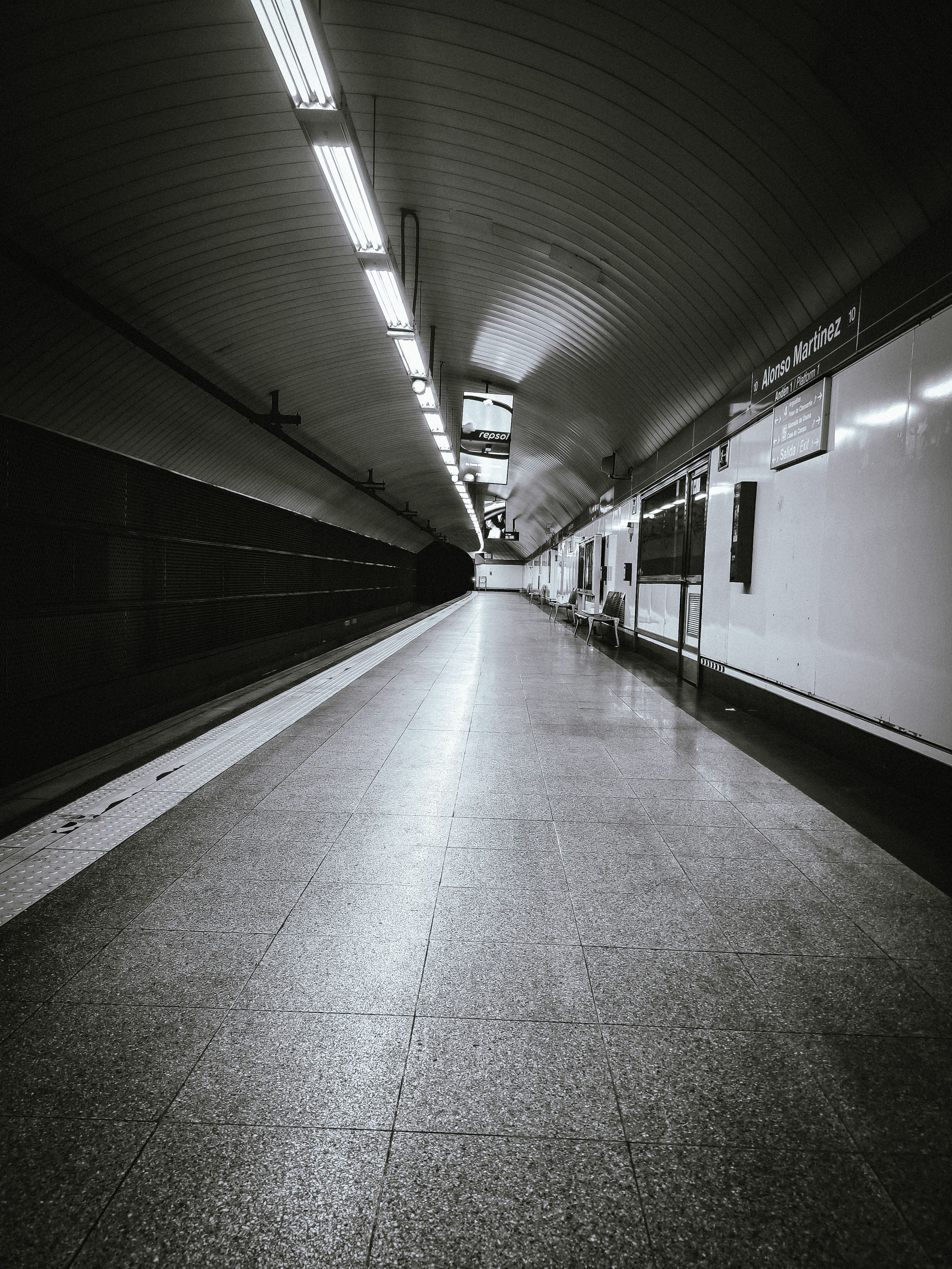 Black and white photo of an empty subway station in Madrid, creating a moody urban atmosphere.
