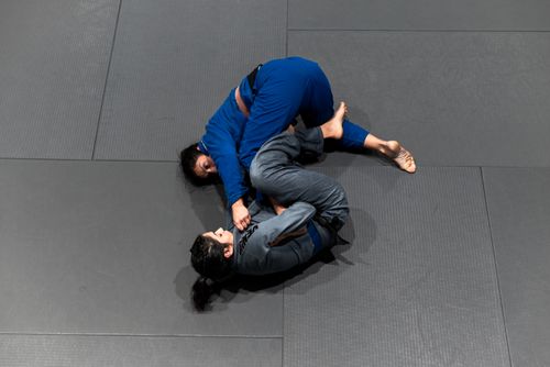 Free Top view of two women engaging in a Brazilian Jiu-Jitsu sparring session on a mat. Stock Photo