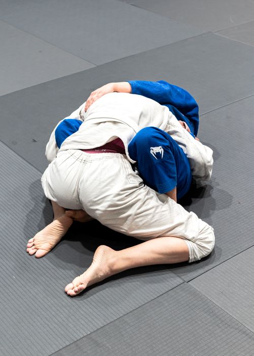 Free Two athletes practicing Brazilian Jiu-Jitsu on a mat indoors. Stock Photo