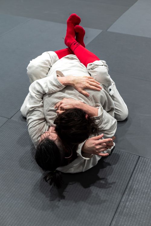 Free Jiu-Jitsu practitioners in grappling position on mat with red socks in Buenos Aires. Stock Photo