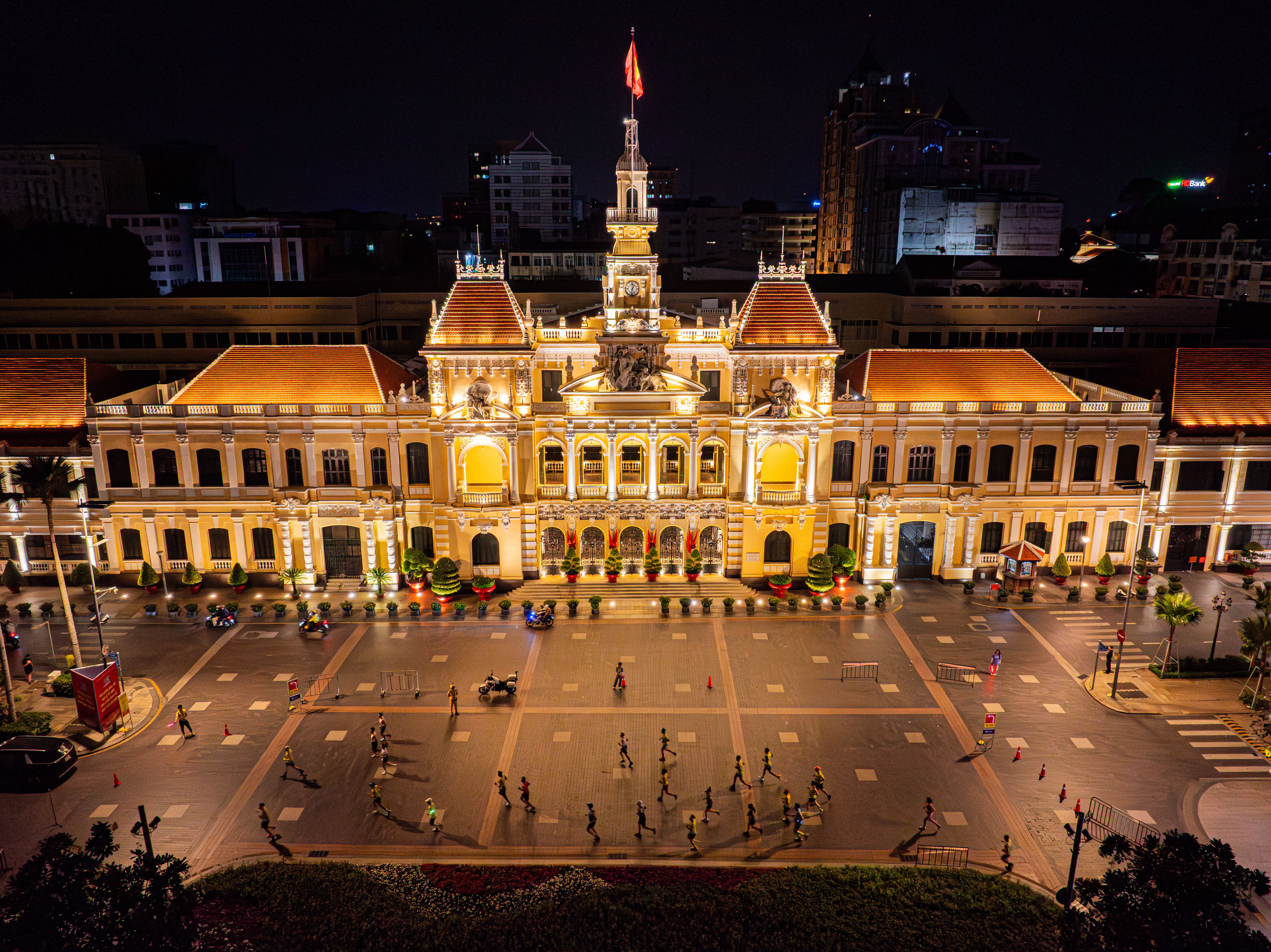 Illuminated Saigon City Hall at night with bustling activity and vibrant lights.