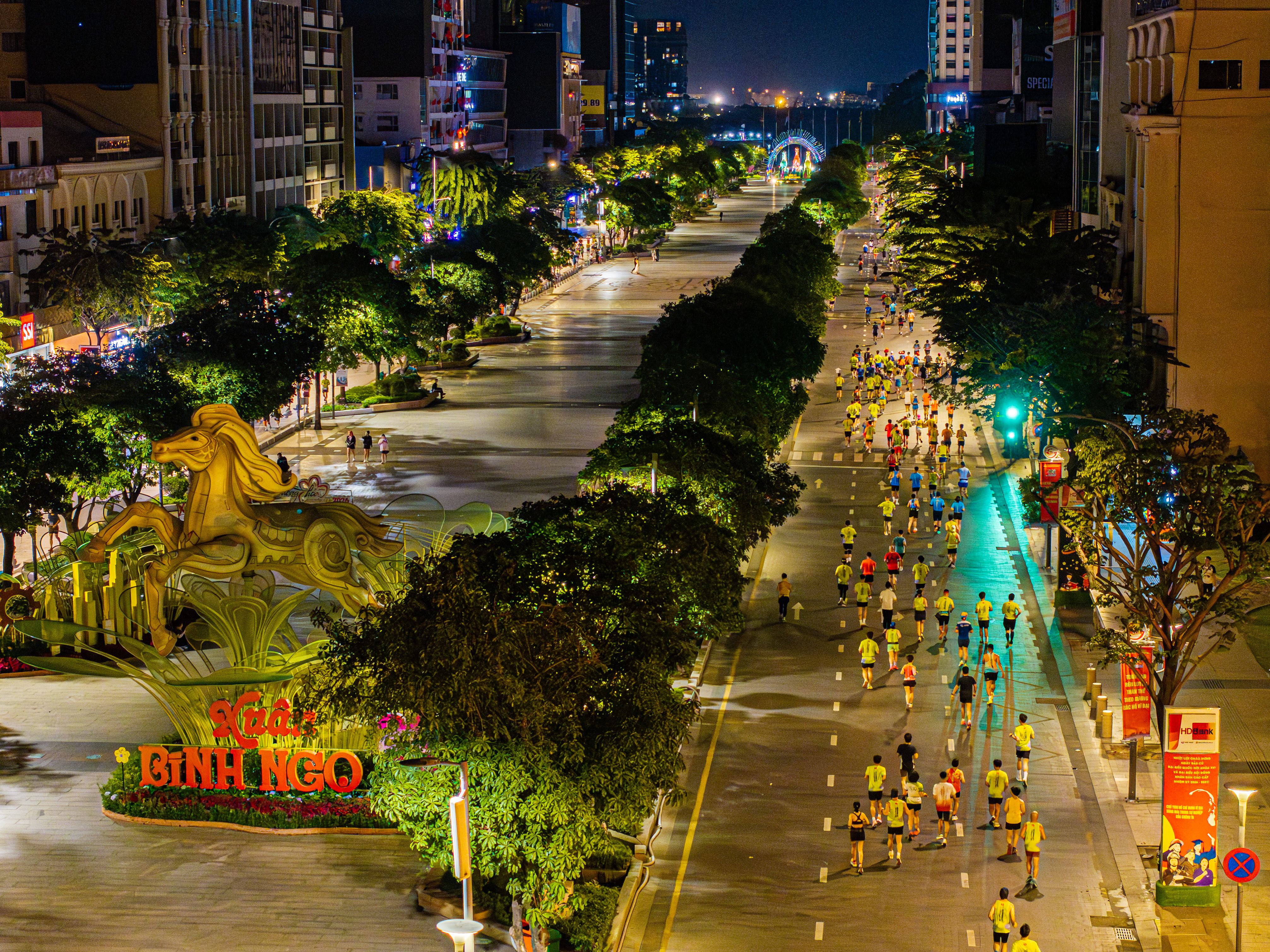 A vibrant nighttime street marathon in Ho Chi Minh City with colorful runners and festive decorations.