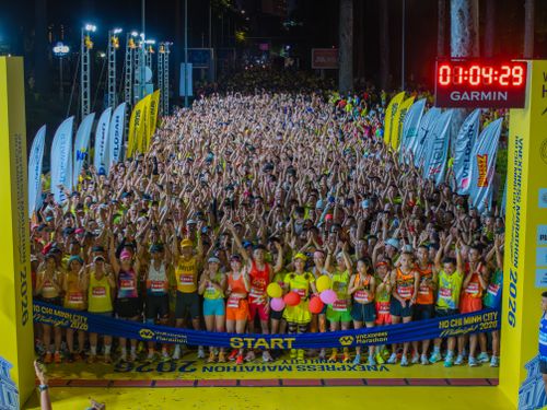 Free Crowds gather at the start of a midnight marathon in Ho Chi Minh City under bright lights. Stock Photo