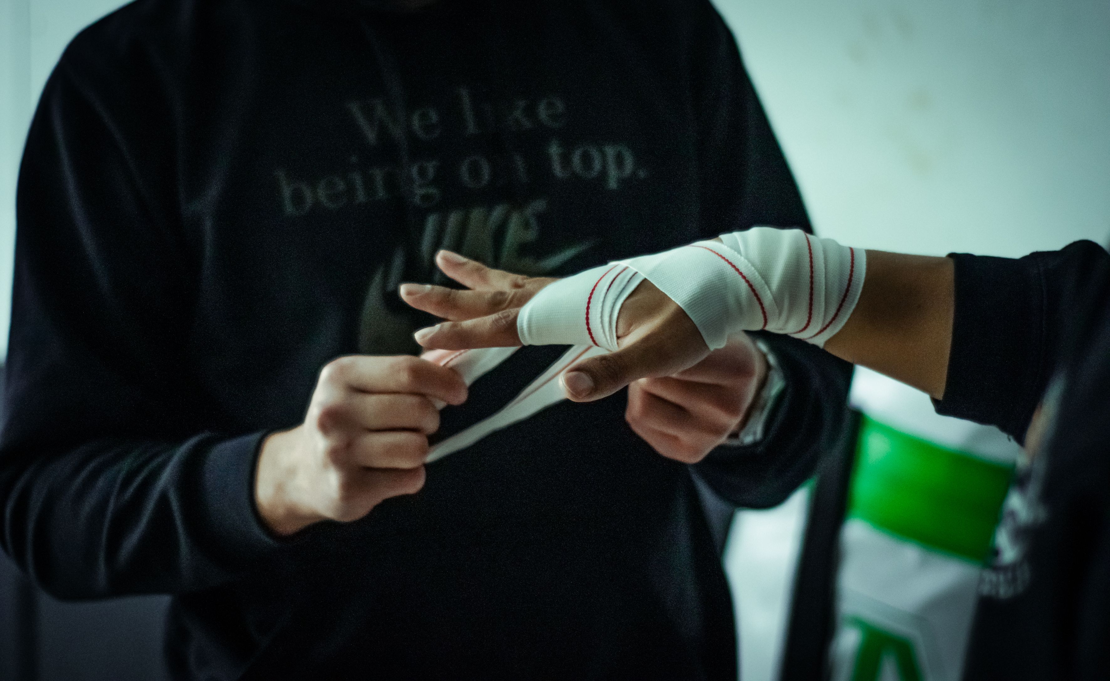 Close-up of hands applying boxing wraps, preparing for training. Focus on hand wrapping technique in gym environment.