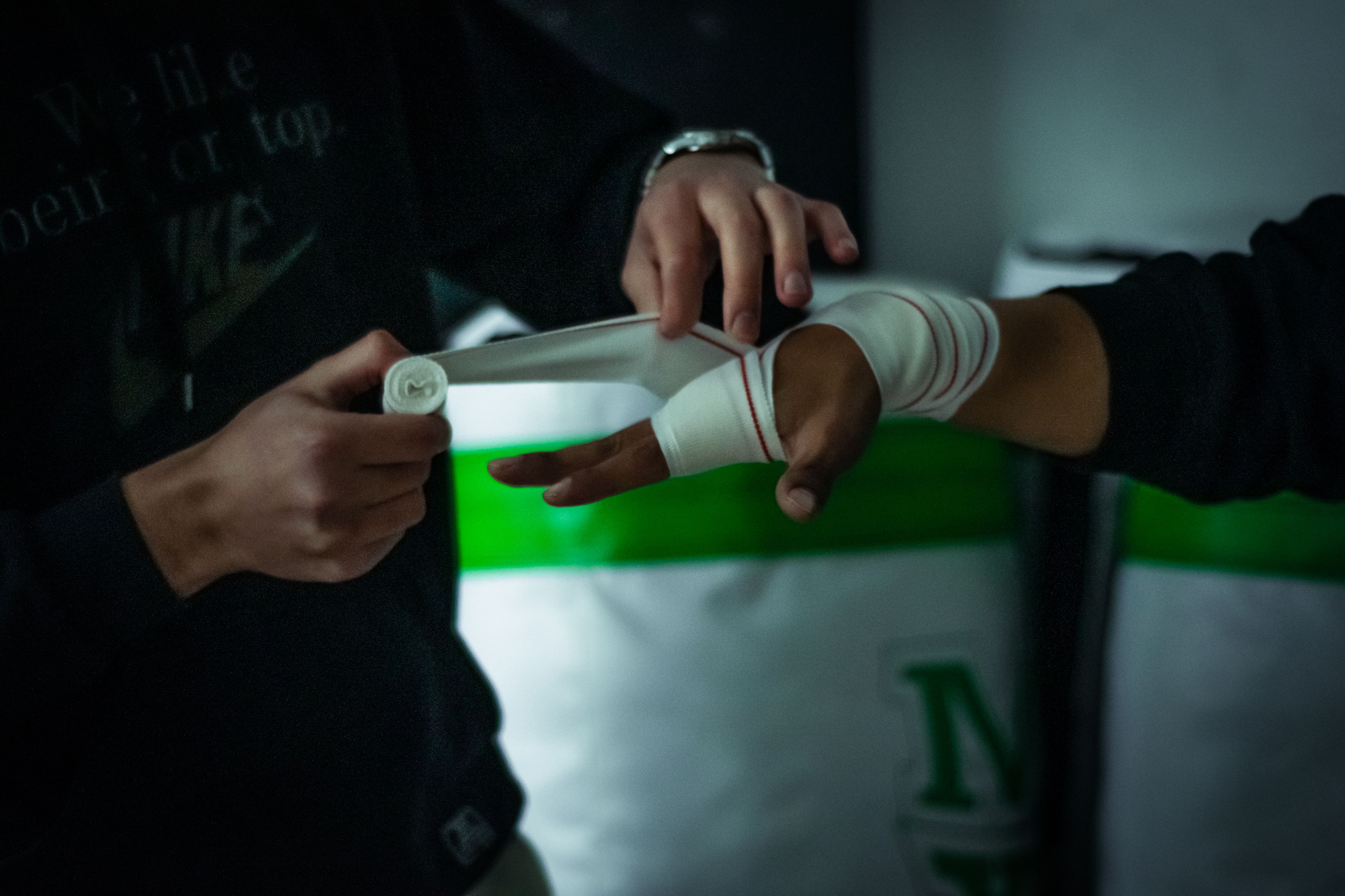 Close-up of a trainer wrapping a boxer's hand in the gym, preparing for a boxing session.