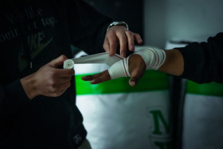 Close-up of a trainer wrapping a boxer's hand in the gym, preparing for a boxing session.