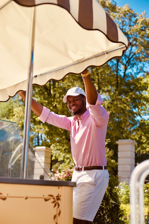 Smiling young black man resting in park near outdoor cafeteria