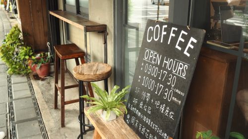Free Cozy outdoor coffee shop entrance with rustic wooden stools and a chalkboard menu. Stock Photo