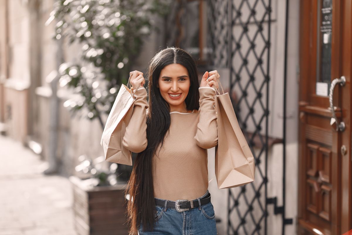 Cheerful woman smiling while walking with shopping bags
