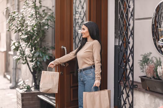 Smiling woman with paper bags leaving a stylish boutique on a sunny day.