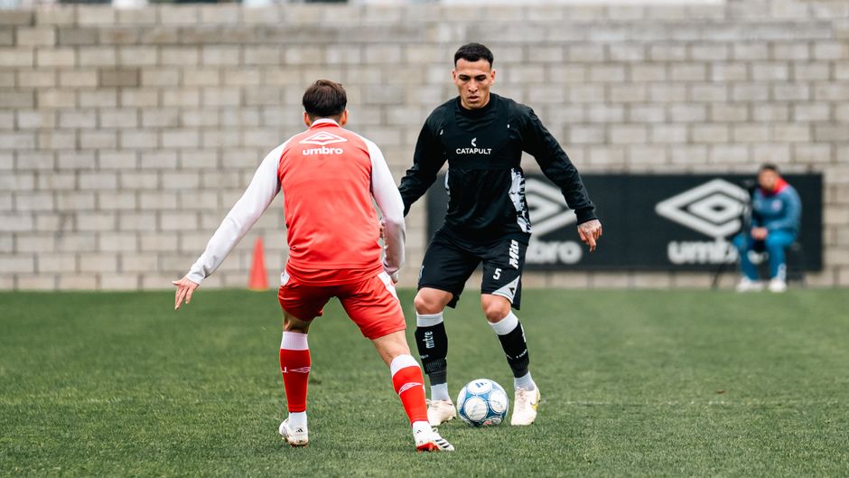 Two soccer players in a training-ground duel, one in red challenging one in dark kit for the ball. — Photo by Franco Monsalvo on Pexels