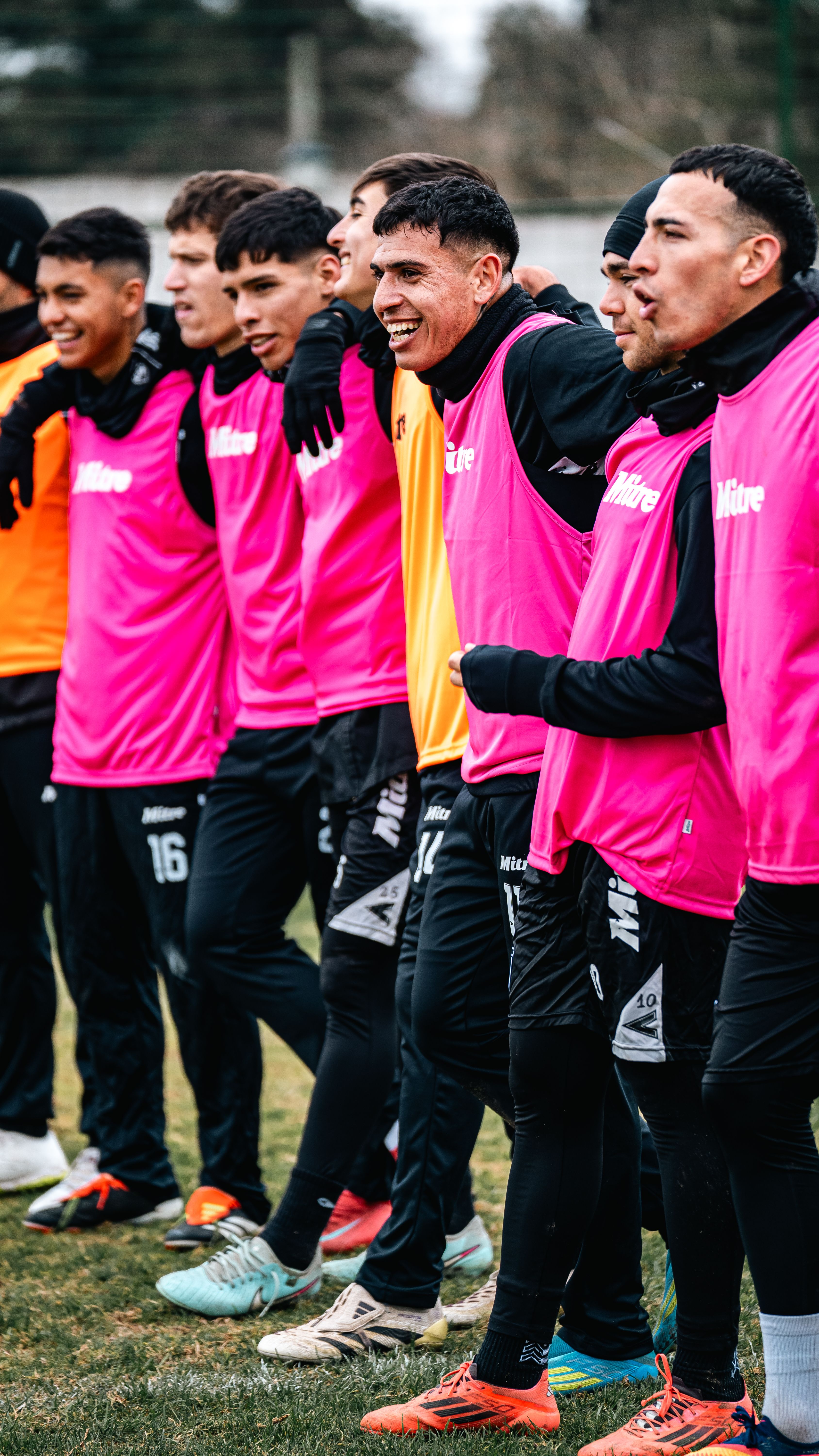 Soccer players in colorful gear enjoying a team bonding session outdoors.