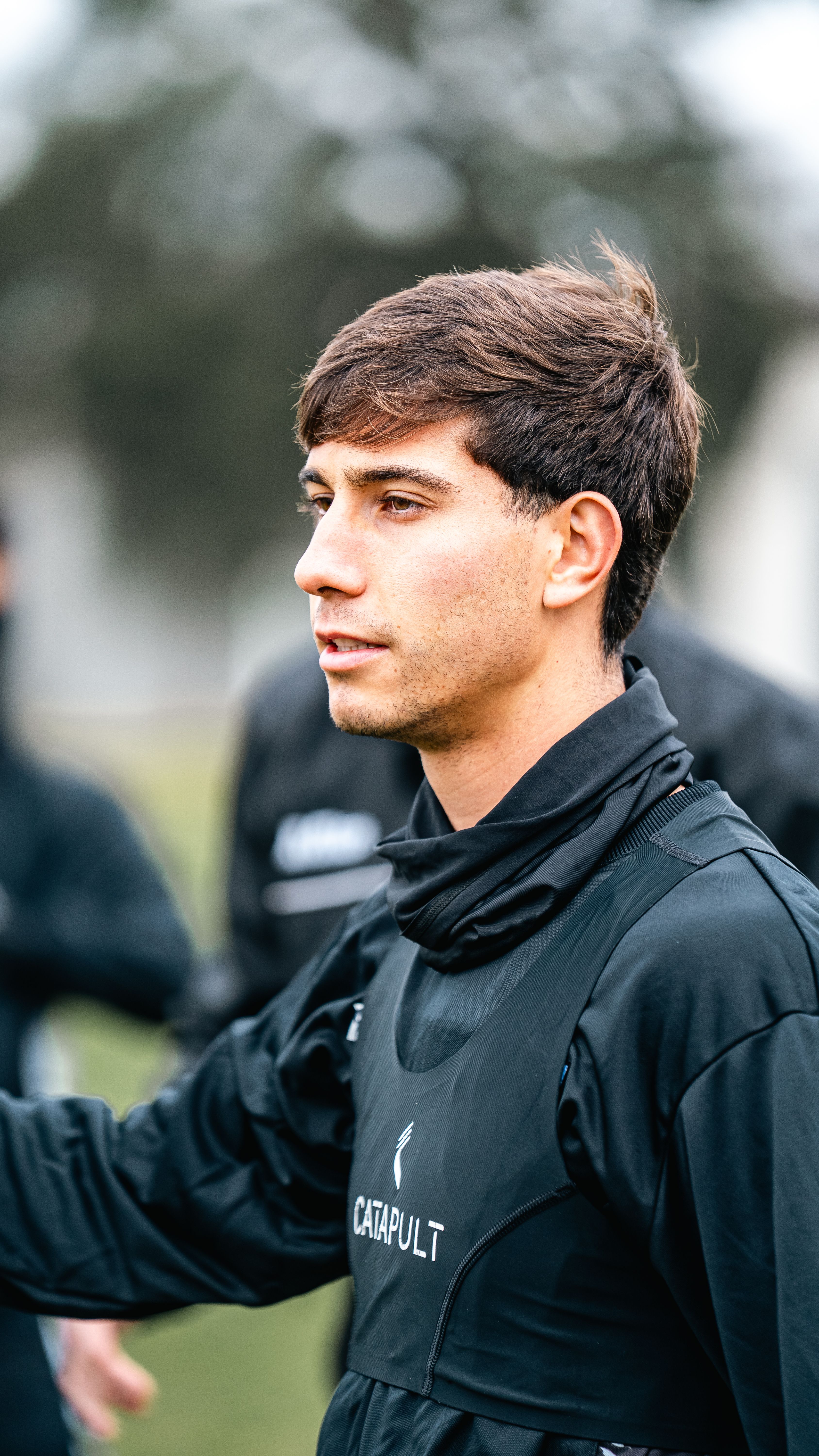 Young male athlete training outdoors in a black sports jersey. Focused and determined expression.