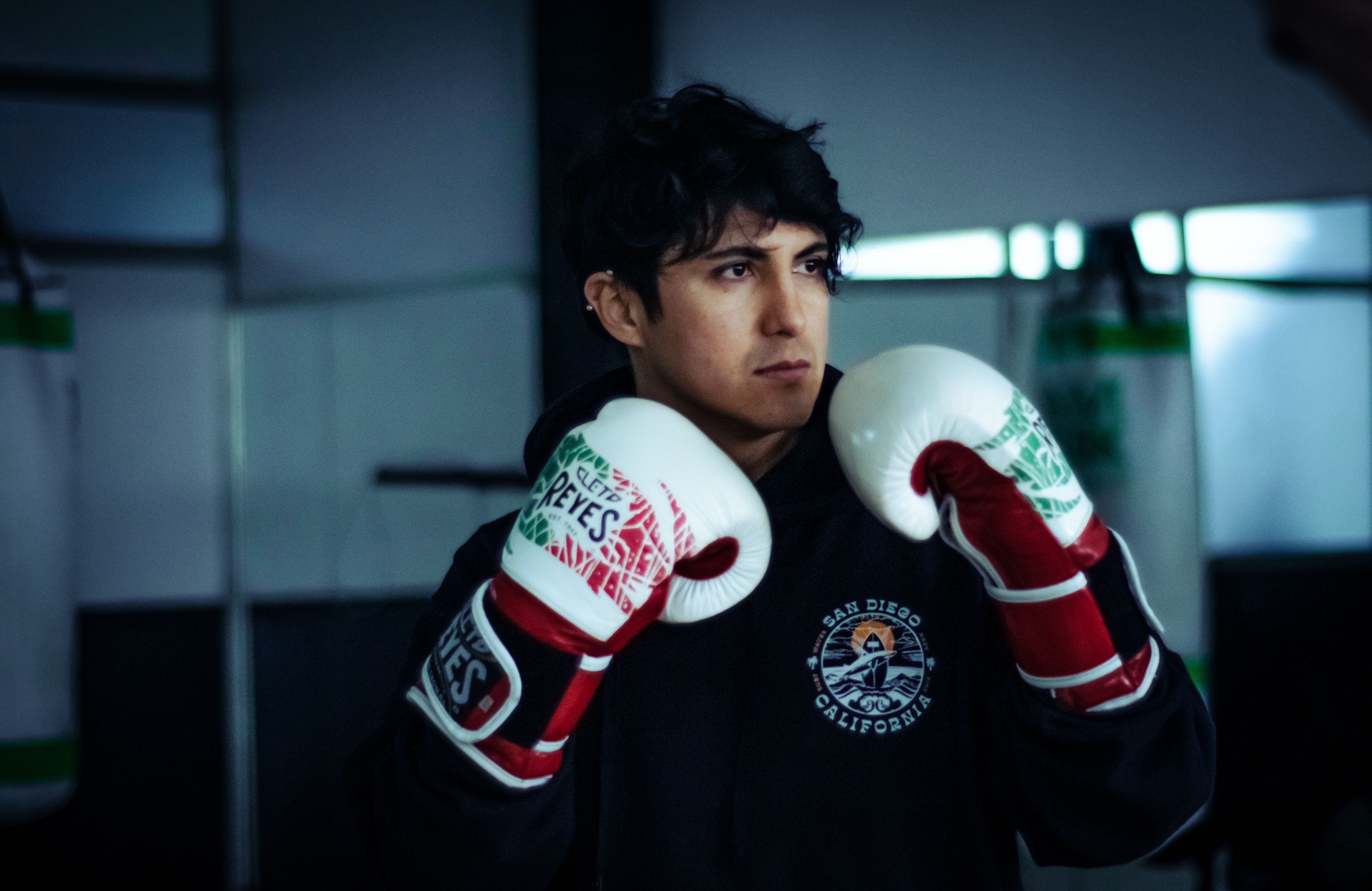 Focused young man in boxing gloves training indoors. Determination and dedication in sports.