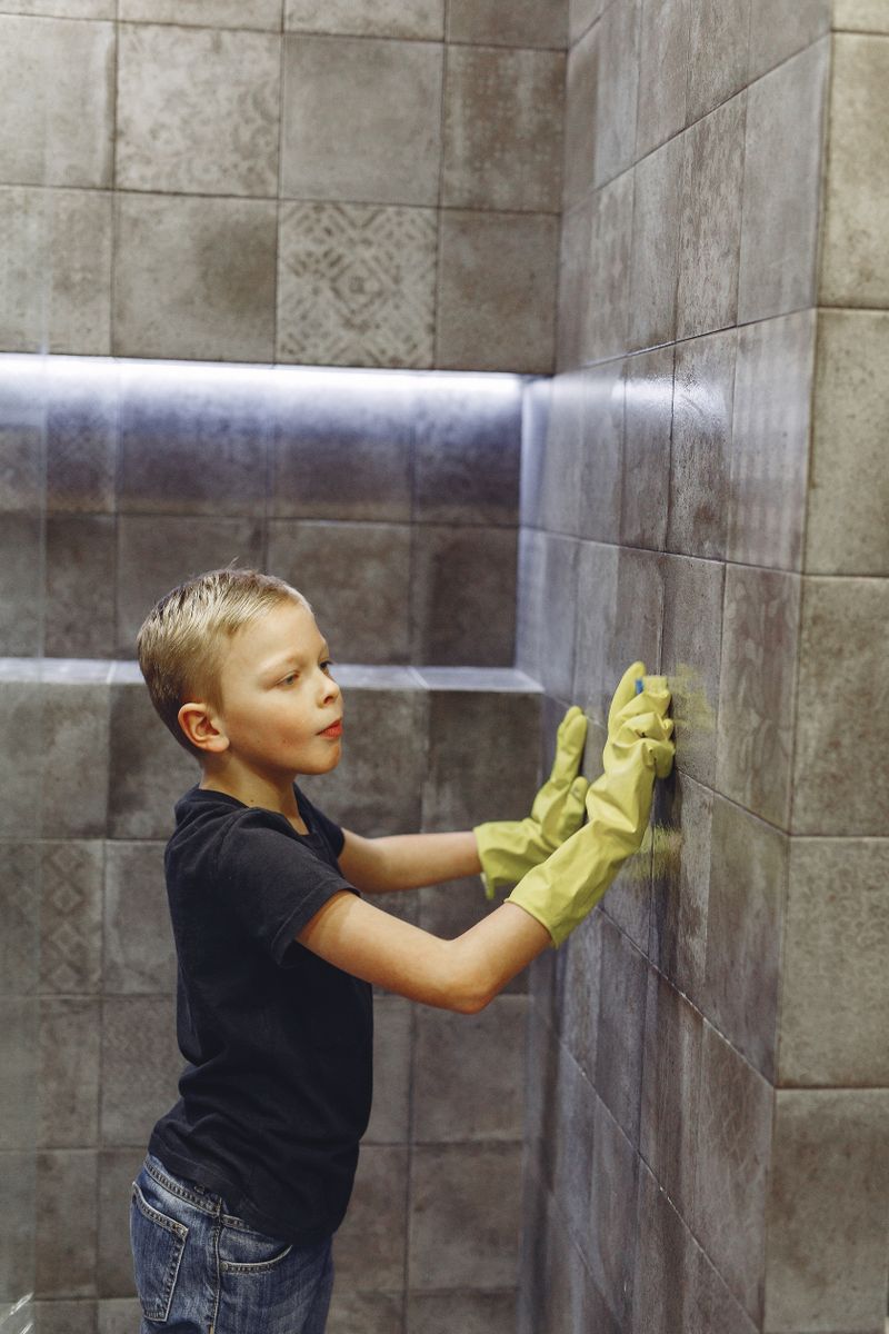 Close-up of hands cleaning bathroom tiles to remove limescale