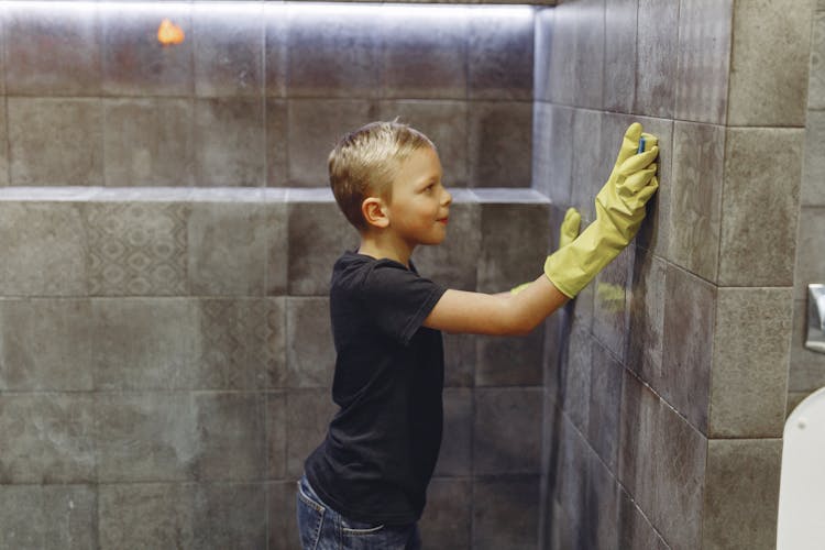 Small Child Washing Tiles In Bathroom Alone