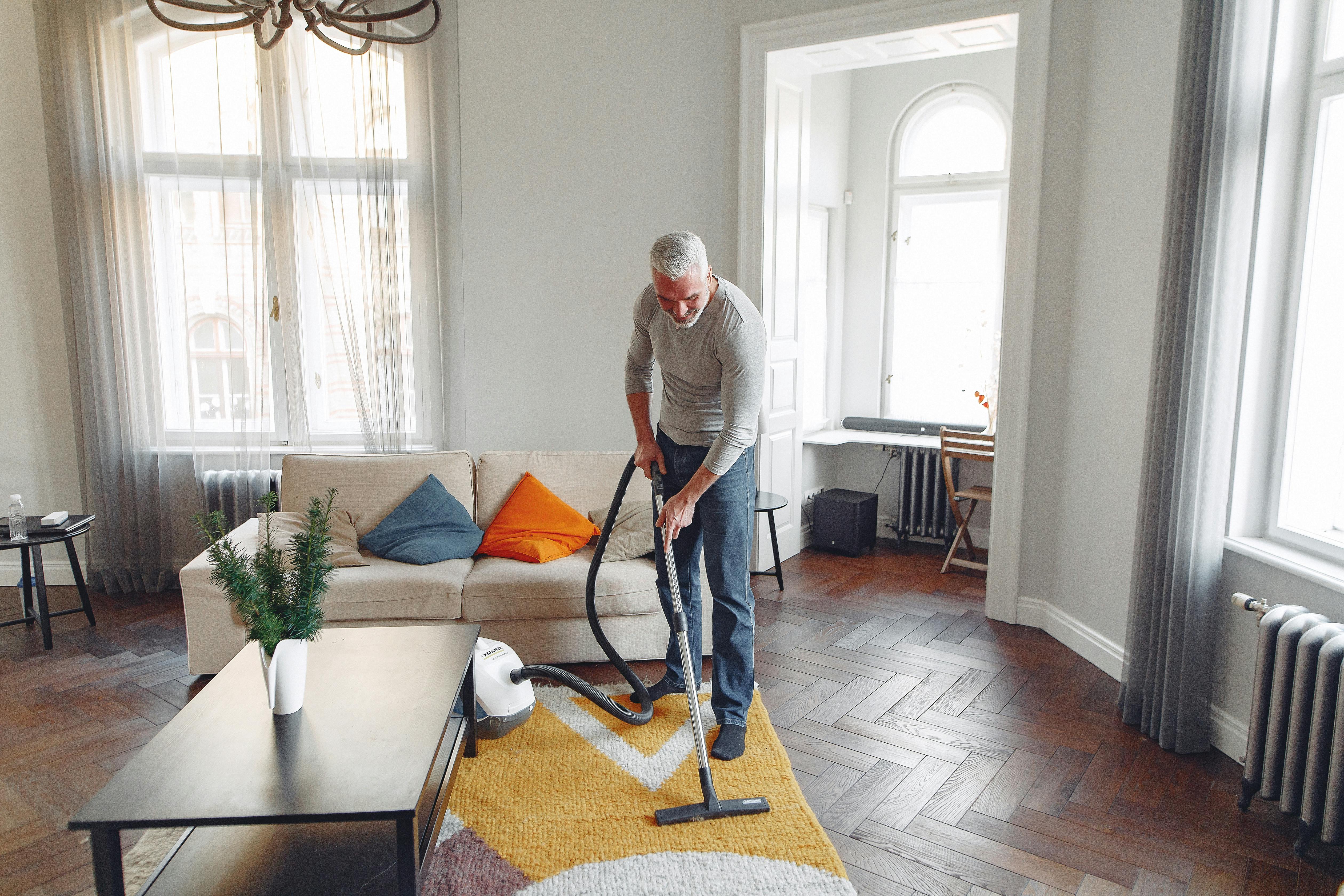 tall man vacuuming floor at apartment