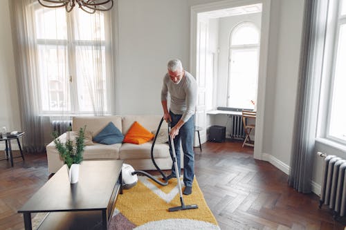 Tall Man Vacuuming a Carpet