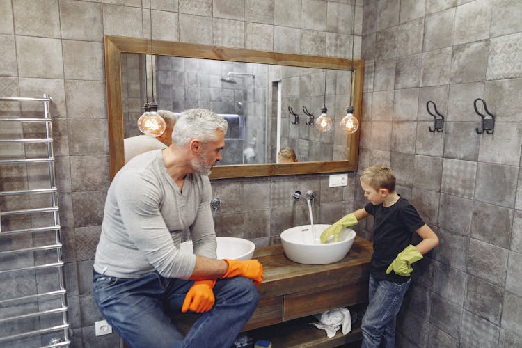 Father With Child Cleaning Sink In Bathroom