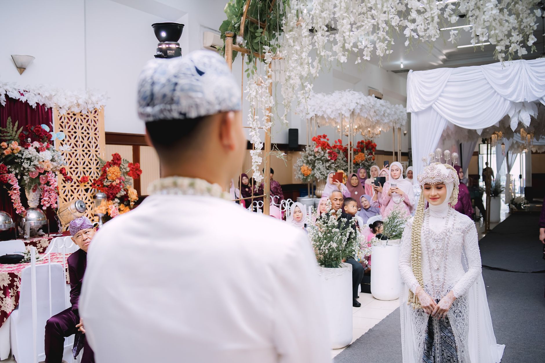 A bride and groom in traditional Sundanese attire at an indoor wedding ceremony in Bandung, Indonesia.