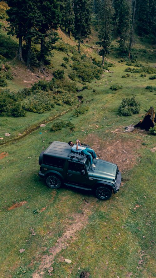 Free A couple enjoys a peaceful moment on a Jeep amidst the lush greenery of Kashmir. Stock Photo