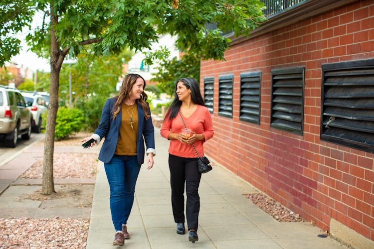 Women Talking While Walking On Sidewalk