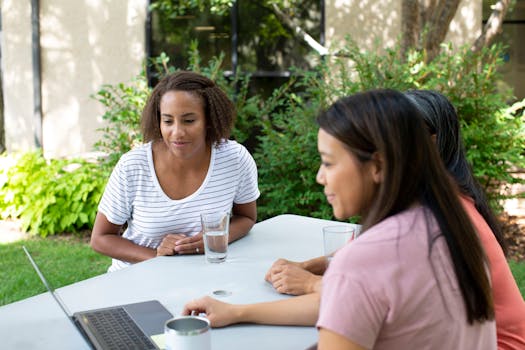 一群女性在户外使用笔记本电脑合作，展现了团队协作精神
