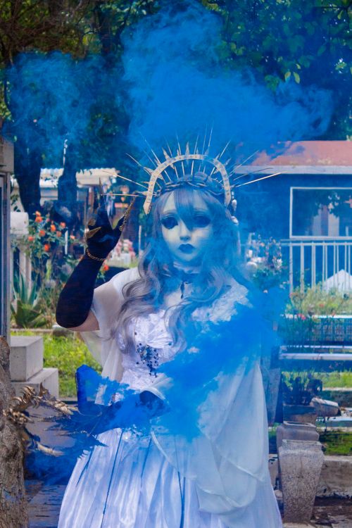Free A person in a dramatic costume with blue smoke in an outdoor setting. Stock Photo