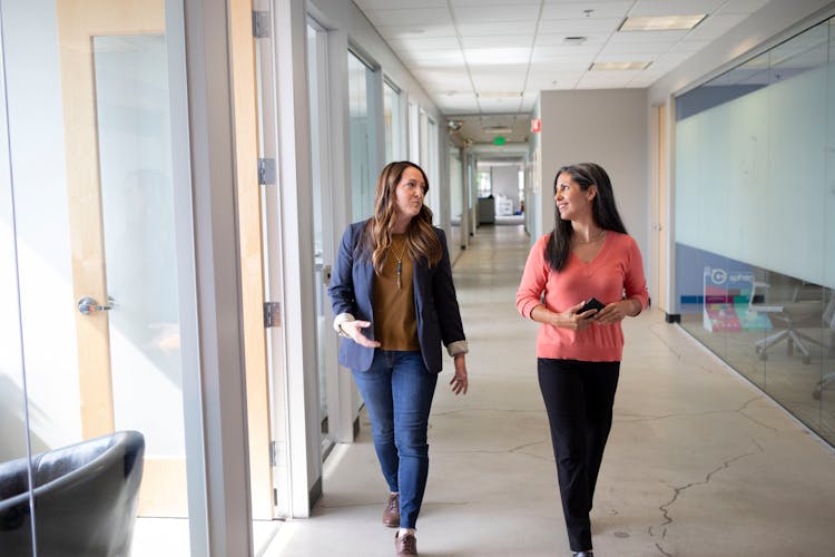 Women Talking While Walking On Hallway