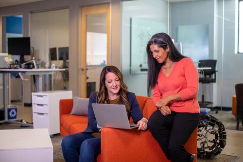 Free Two women working collaboratively on a laptop in a modern office environment, conveying teamwork and productivity. Stock Photo