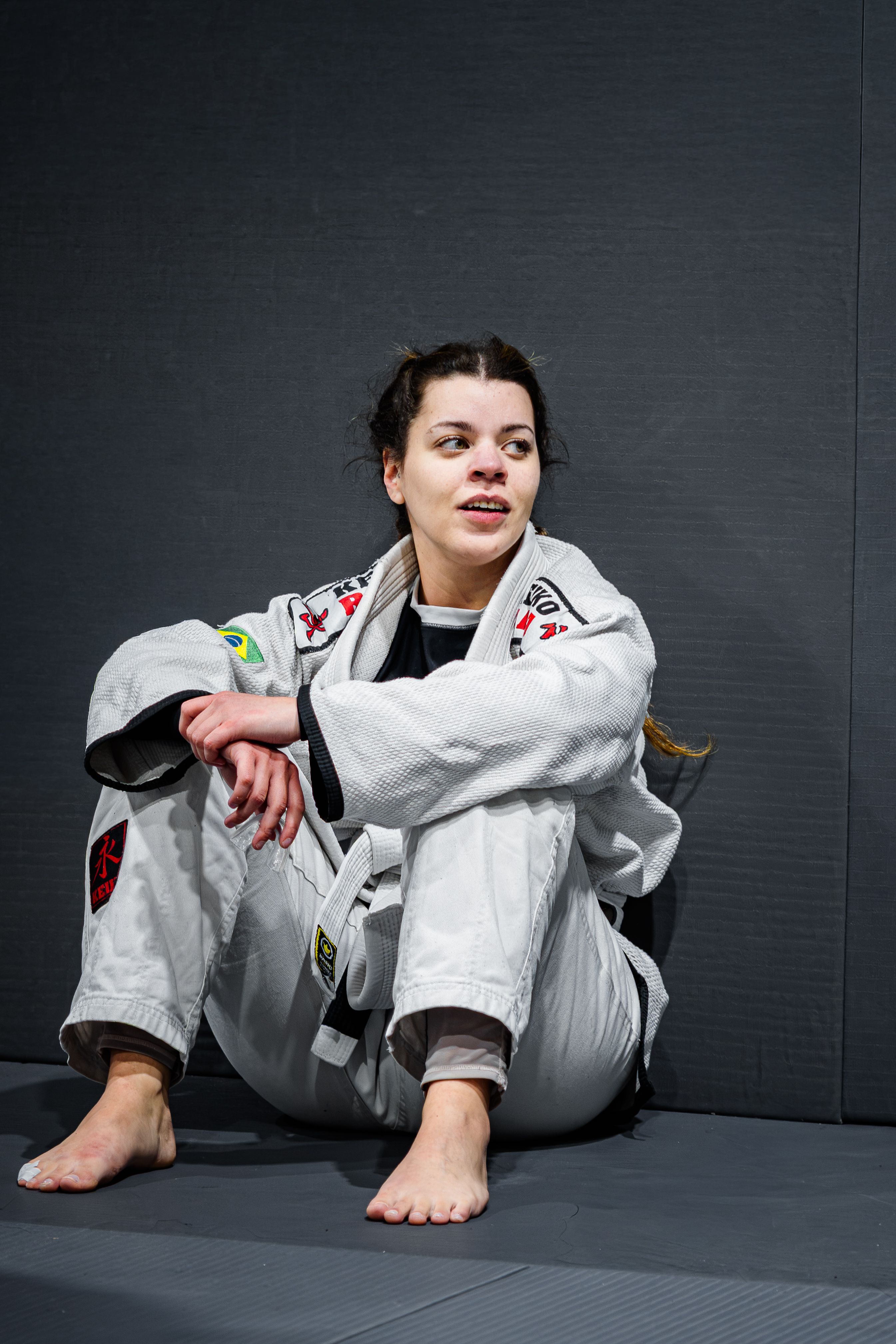 Female martial artist in a jiu jitsu gi taking a break after training indoors.