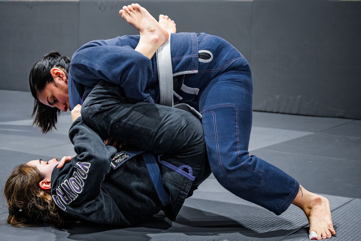 Two athletes sparring on the mat during a jiu-jitsu session.