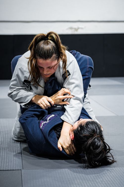 Free Two women practicing Brazilian Jiu-Jitsu in a dynamic grappling session indoors. Stock Photo