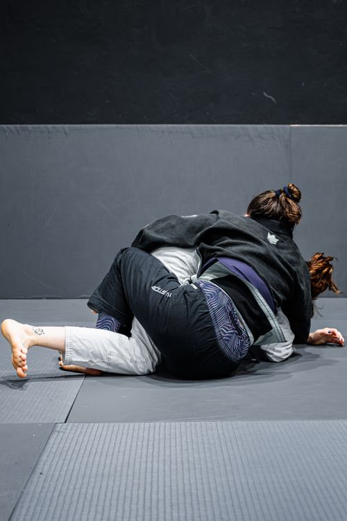 Free Two adults practicing Brazilian Jiu-Jitsu on padded mats indoors. Stock Photo