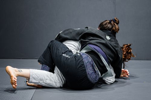 Free Two women engaged in a jiu-jitsu training session, demonstrating grappling techniques on a gym mat. Stock Photo
