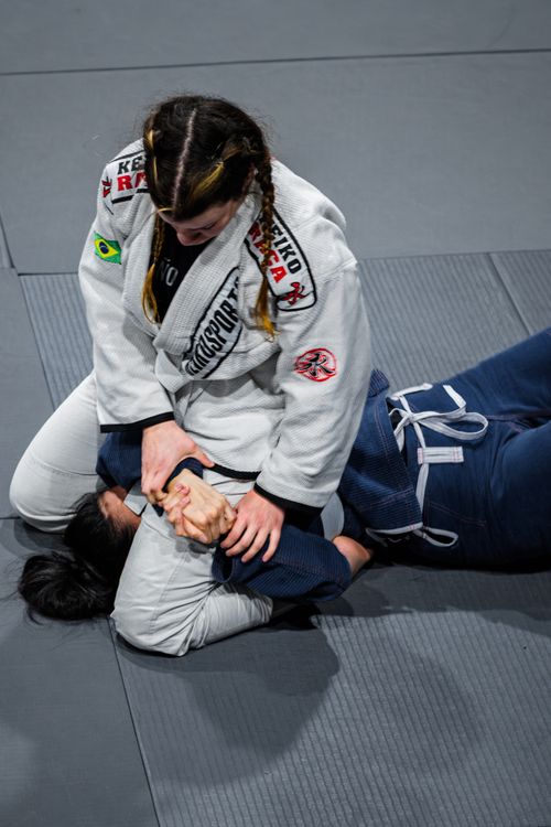 Free Two athletes practicing Brazilian Jiu-Jitsu on a mat in a gym environment. Stock Photo