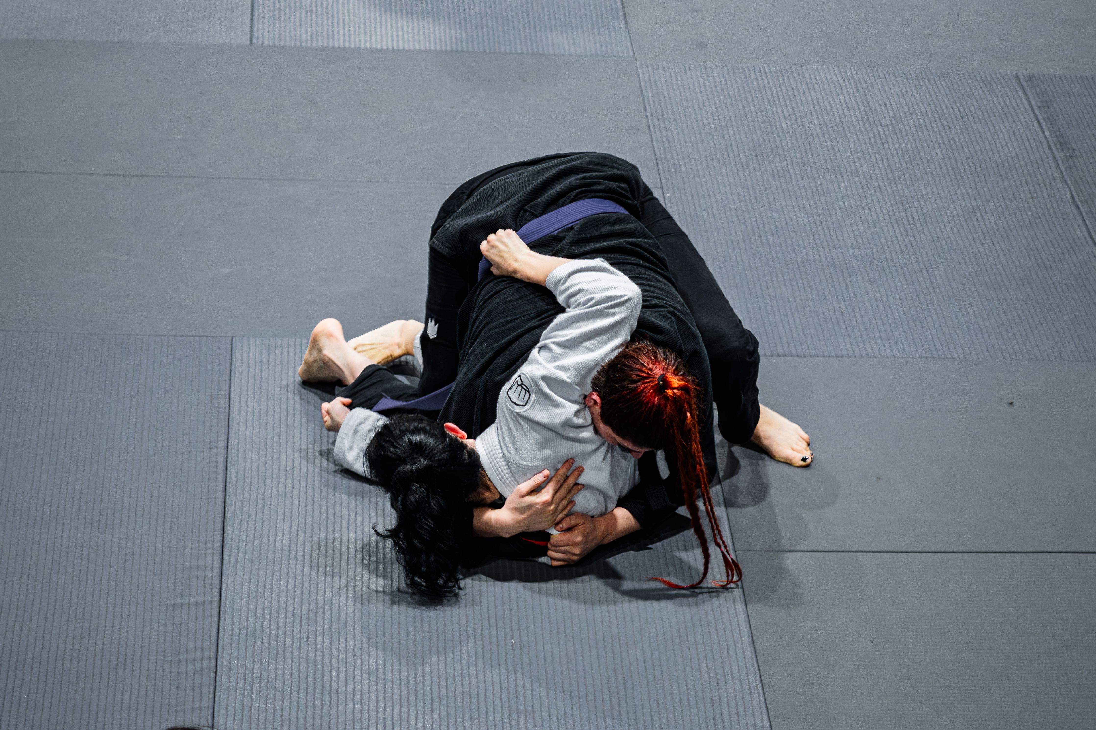 Two women practice Brazilian Jiu-Jitsu techniques in a gym in Buenos Aires.