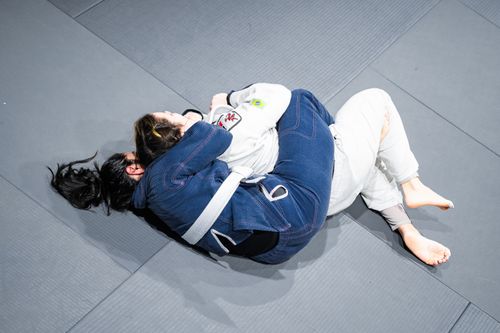 Free Two women practicing Brazilian Jiu-Jitsu grappling techniques indoors. Stock Photo