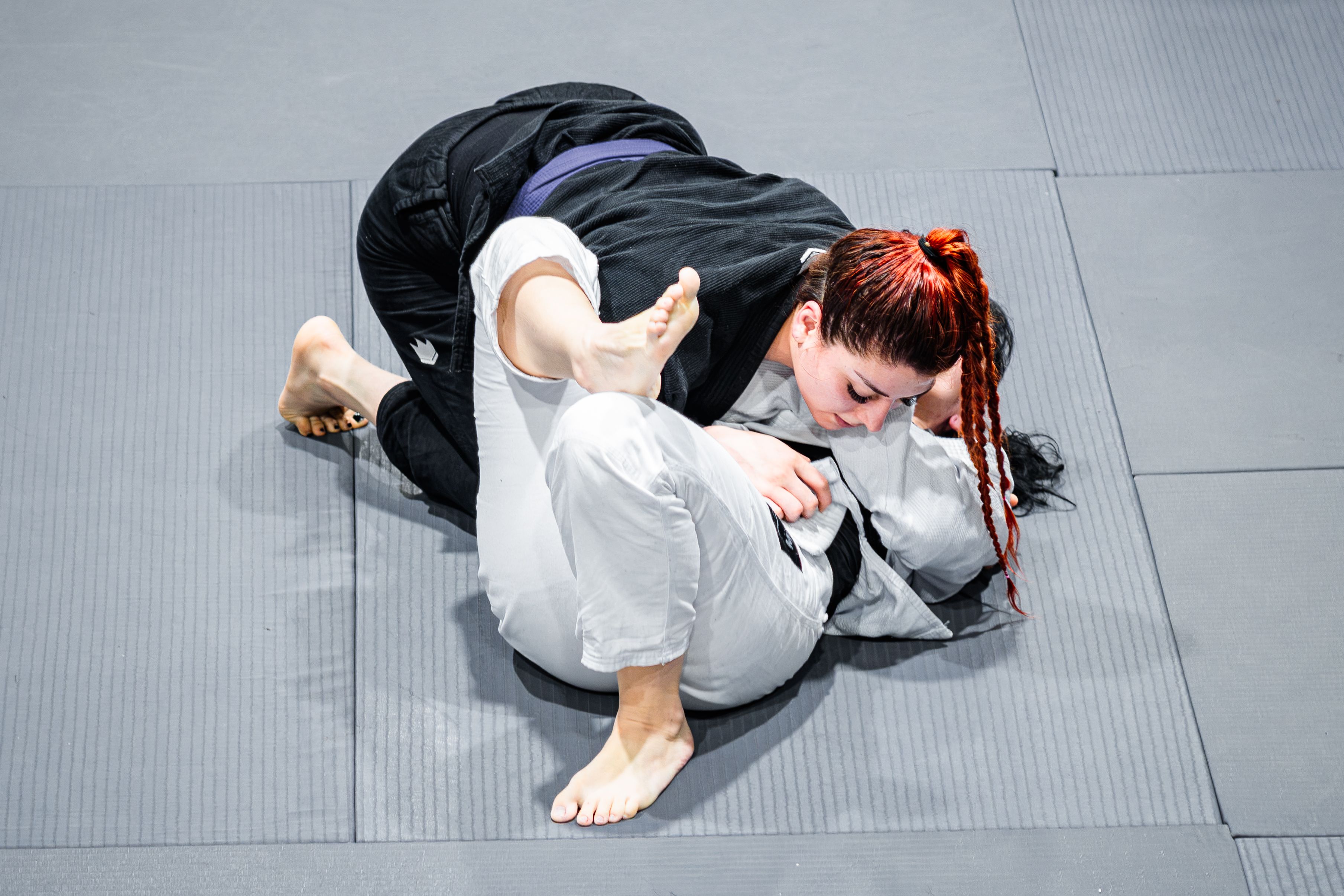 Two women engage in Brazilian Jiu-Jitsu grappling on a mat in Buenos Aires, showcasing martial arts techniques.