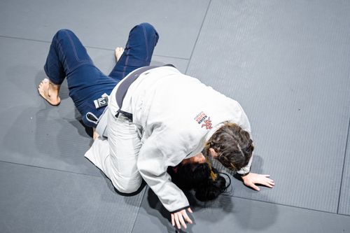 Free Two female athletes engage in Brazilian Jiu-Jitsu on a studio mat, showcasing grappling techniques. Stock Photo