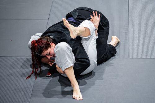 Free Two athletes engage in a dynamic grappling move during a martial arts match, showcasing technique and agility. Stock Photo