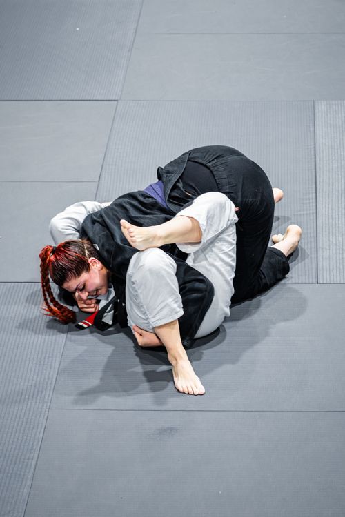 Free A competitive Brazilian Jiu-Jitsu match with two athletes grappling on tatami mats, showcasing martial arts skills. Stock Photo