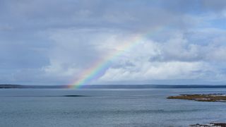 Rainbow arching across a shallow bay, photo by Stuart Robinson on Pexels