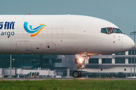 Side view of a cargo airplane with distinct branding, preparing for takeoff at an airport terminal.