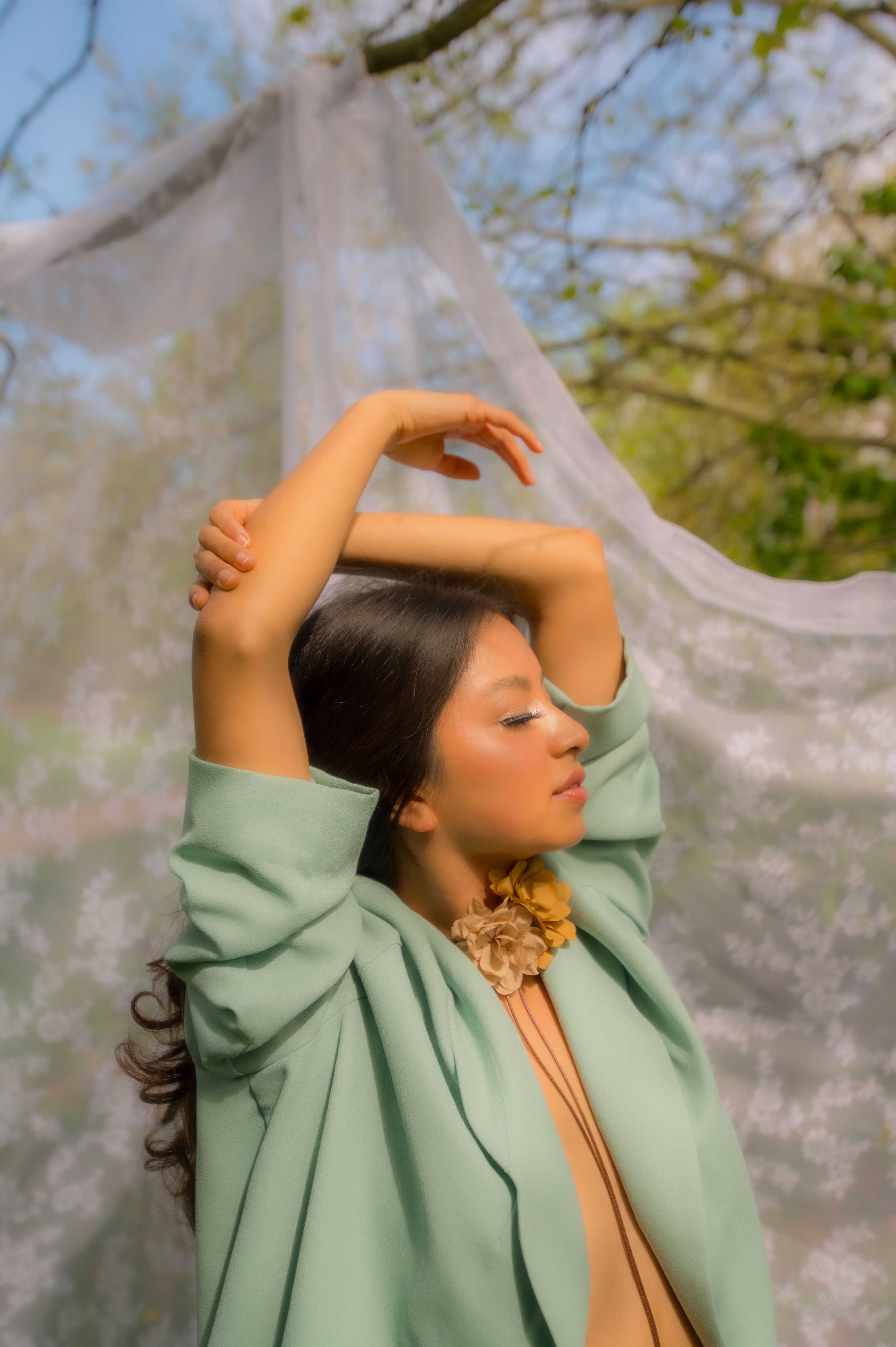 A serene portrait of a woman outdoors in Berlin, showcasing elegance and springtime foliage.