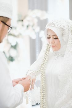 A bride and groom exchanging rings during a traditional Indonesian wedding ceremony. - Fotografer Sidoarjo