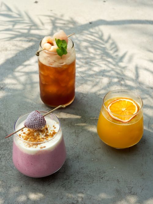 Free Three colorful drinks featuring an iced tea, smoothie, and orange juice garnished beautifully. Stock Photo