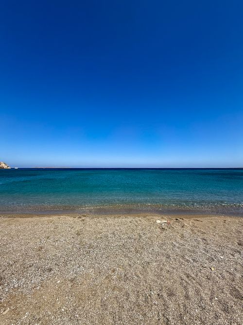 Free A tranquil Mediterranean beach under a clear blue sky, showcasing pristine water and sandy shore. Stock Photo
