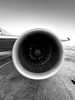 Black and white close-up of an airplane jet engine on the tarmac, showcasing engineering details.